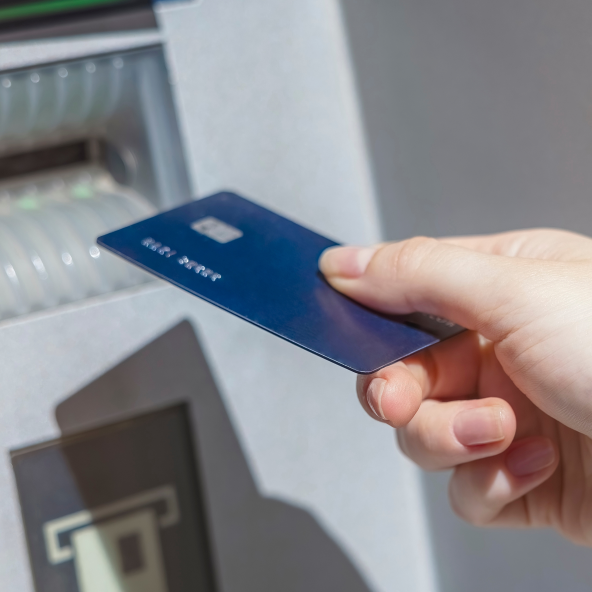 Zbliżenie na granatową kartę płatniczą, którą ktoś trzyma w prawym ręku w próbuje włożyć do bankomatu w Galerii Echo.